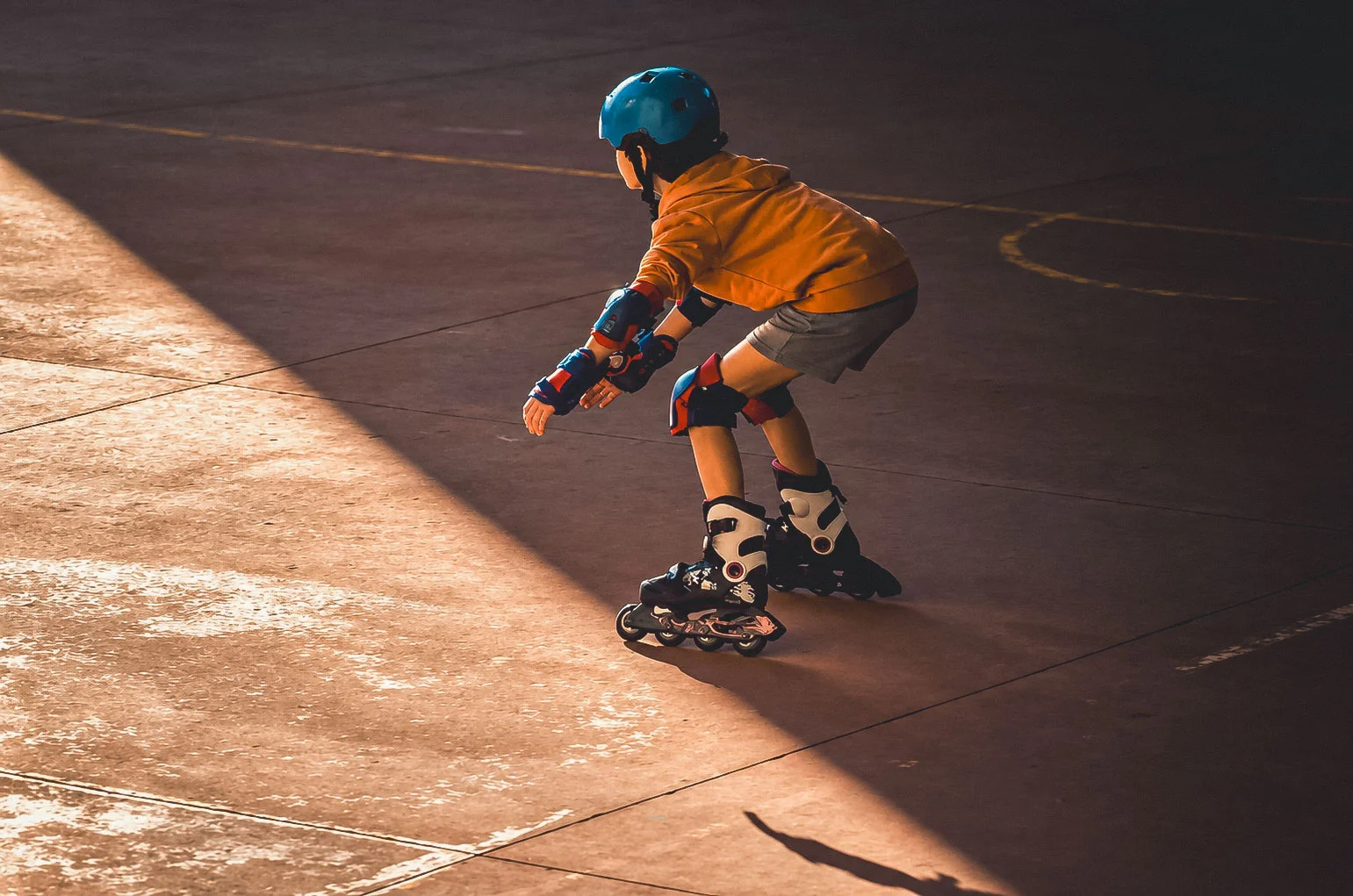 Haur bat kaskoarekin eta babesekin lerroko patinetan ibiltzen